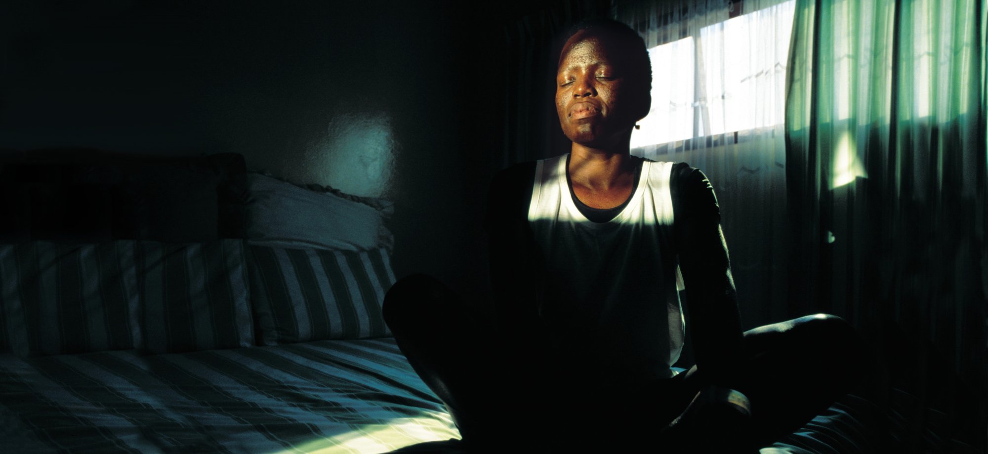 An AIDS survivor in Soweto who has regained her mobility thanks to medication, meditates in her room.